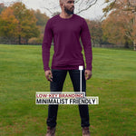 An upper body shot of a tall athletic guy standing in a park wearing a dark purple extra long tall long sleeve t-shirt and showing  the Just Tall minimalist monogram logo.