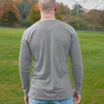 A shot from behind of a tall athletic guy wearing a long sleeve light grey tall t-shirt.