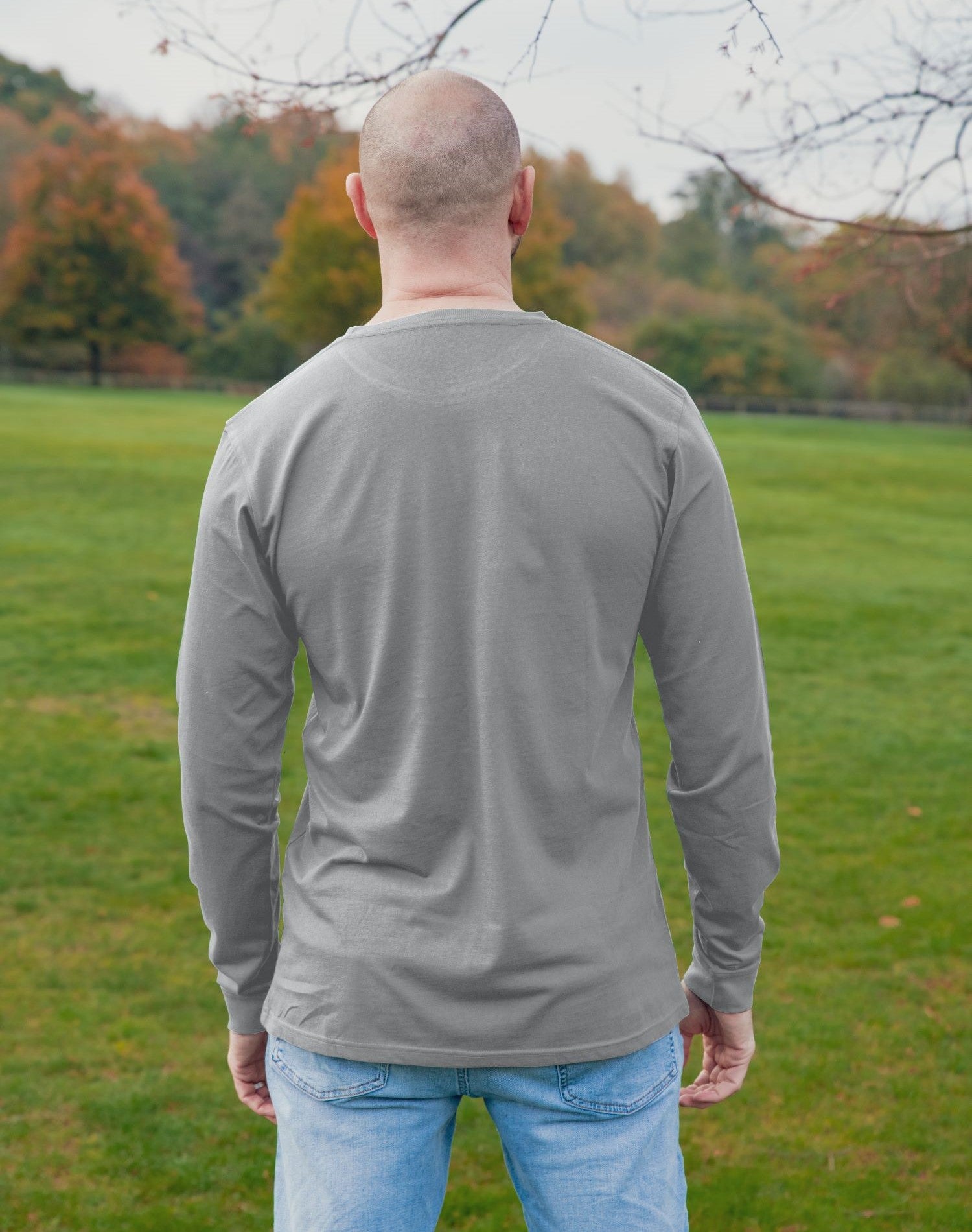 A shot from behind of a tall athletic guy wearing a long sleeve light grey tall t-shirt.