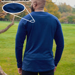 A shot from behind of a tall slim guy in a park wearing an extra long sleeve long sleeve tall t-shirt in navy.