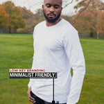 An upper body shot of a tall athletic guy standing in a park wearing a white extra long tall long sleeve t-shirt and looking down at the Just Tall minimalist monogram logo.