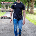 A tall man standing on a park path wearing a black fitted short-sleeve t-shirt and blue jeans, with text callouts describing the shirt's fit and length.