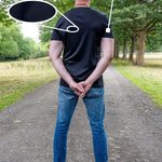 A tall man standing on a park path viewed from behind, wearing a black fitted short-sleeve t-shirt and blue jeans. Text overlays highlight the product features: '100% Mercerised Organic Cotton Planet Friendly' with a fabric swatch circle, and 'Fitted Sleeves Skinny Arm Fit' with a pointer to the sleeve.