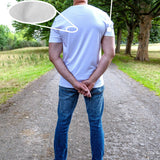 A tall man standing outdoors on a gravel path wearing a white fitted short-sleeve t-shirt and blue jeans, with text overlays highlighting the shirt's features including '100% Mercerised Organic Cotton Planet Friendly' and 'Fitted Sleeves Skinny Arm Fit'.