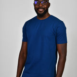 A tall and slim man in the studio standing in front of a light background. The smiling model is wearing an extra long slim navy blue t-shirt in a size large. The tall navy blue t-shirt features a 3" longer body, 100% organic cotton, and is soft & preshrunk. The navy blue t-shirt is ideal for tall slim men 6'2"+.