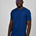 A tall and slim man in the studio standing in front of a light background. The smiling model is wearing an extra long slim navy blue t-shirt in a size large. The tall navy blue t-shirt features a 3" longer body, 100% organic cotton, and is soft & preshrunk. The navy blue t-shirt is ideal for tall slim men 6'2"+.