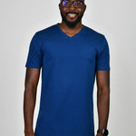 A tall and slim man in the studio standing in front of a light background. The smiling model is wearing an extra long slim navy blue v-neck t-shirt in a size large. The tall navy blue v-neck t-shirt features a 3" longer body, 100% organic cotton, and is soft & preshrunk. The navy blue v-neck t-shirt is ideal for tall slim men 6'2"+.