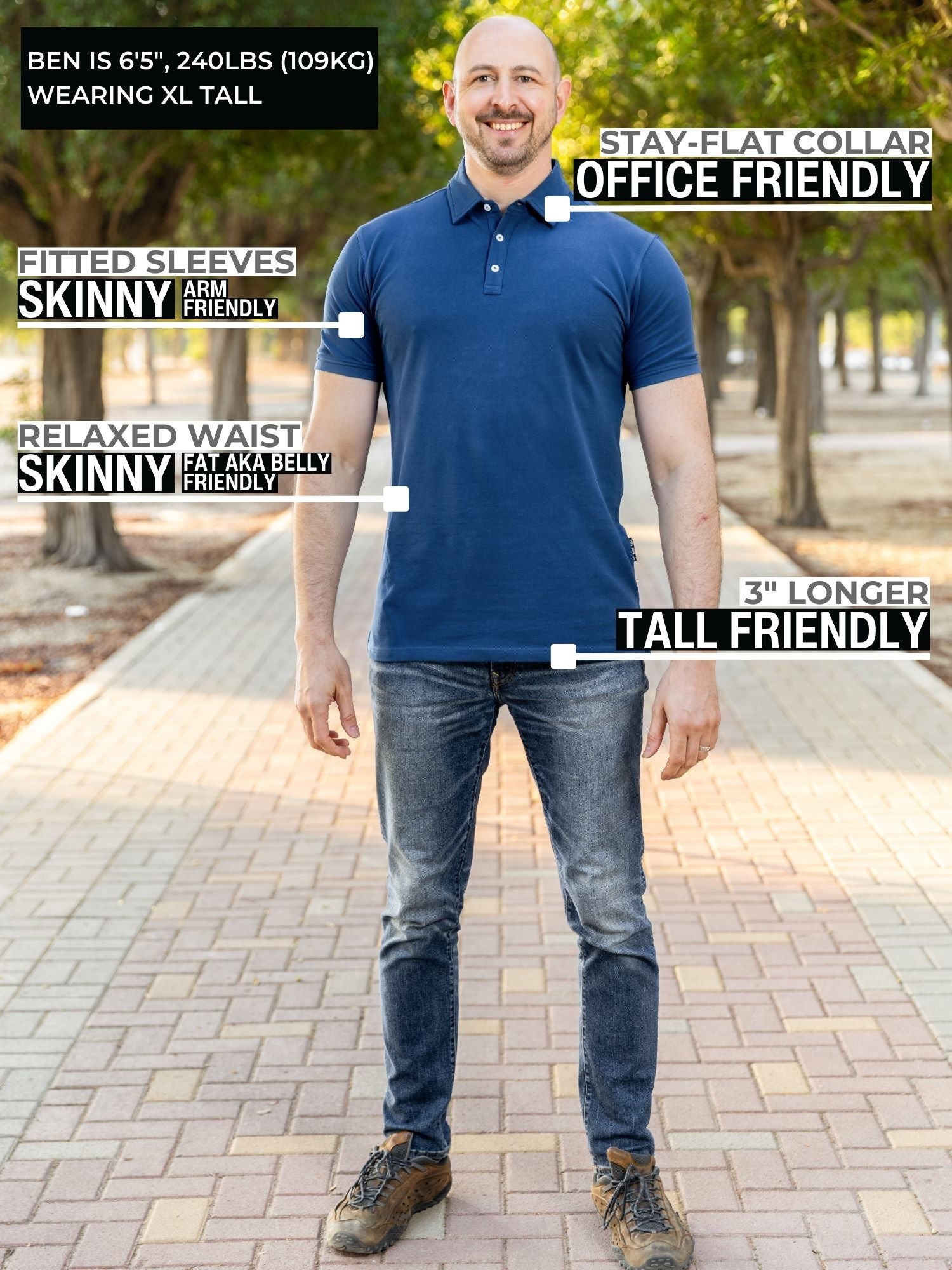 A head to toe shot of a tall athletic man in a park wearing a navy XL tall polo shirt and smiling.