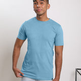 A studio shot of a tall slim guy wearing a medium tall slim pastel blue t-shirt.