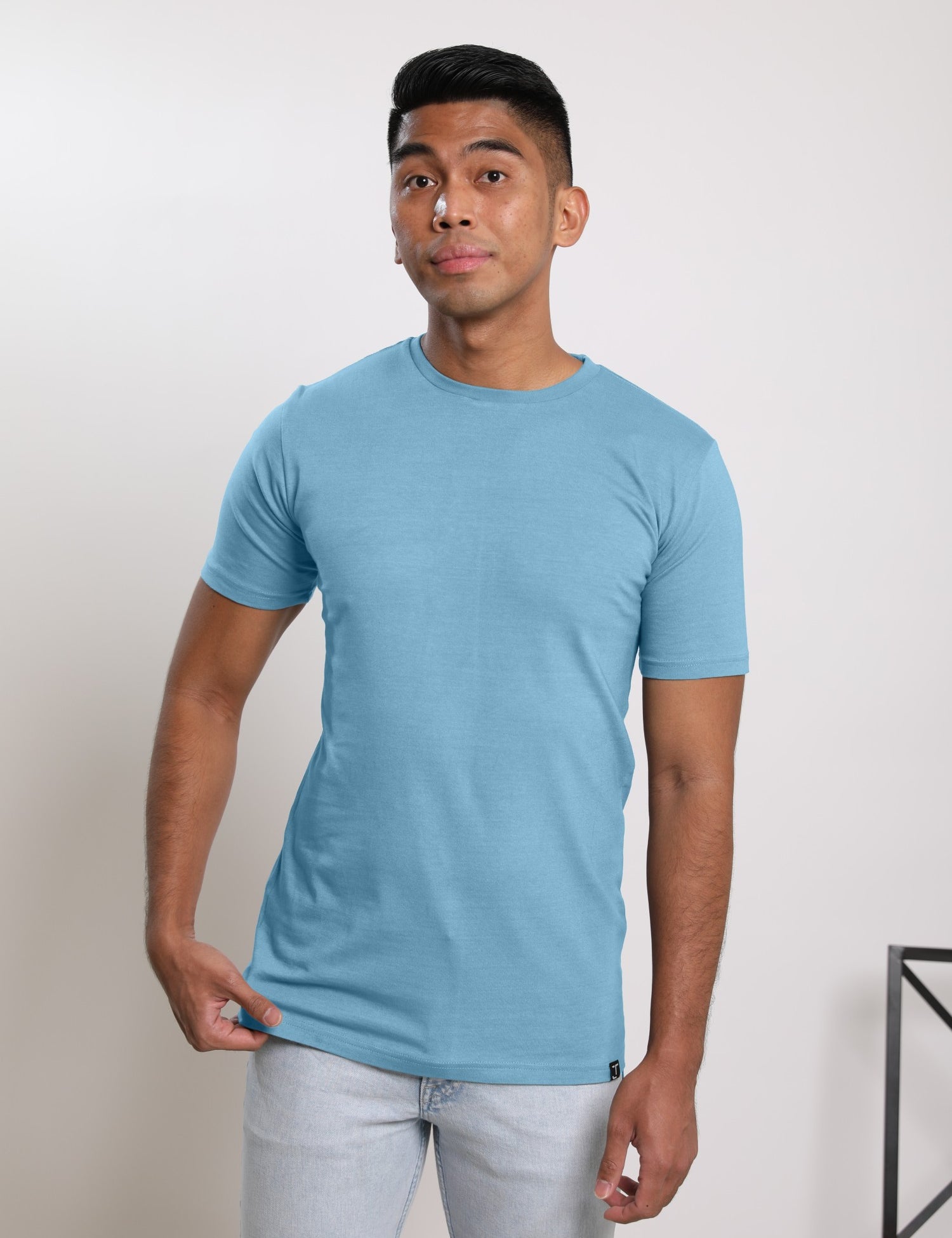 A studio shot of a tall slim guy wearing a medium tall slim pastel blue t-shirt.