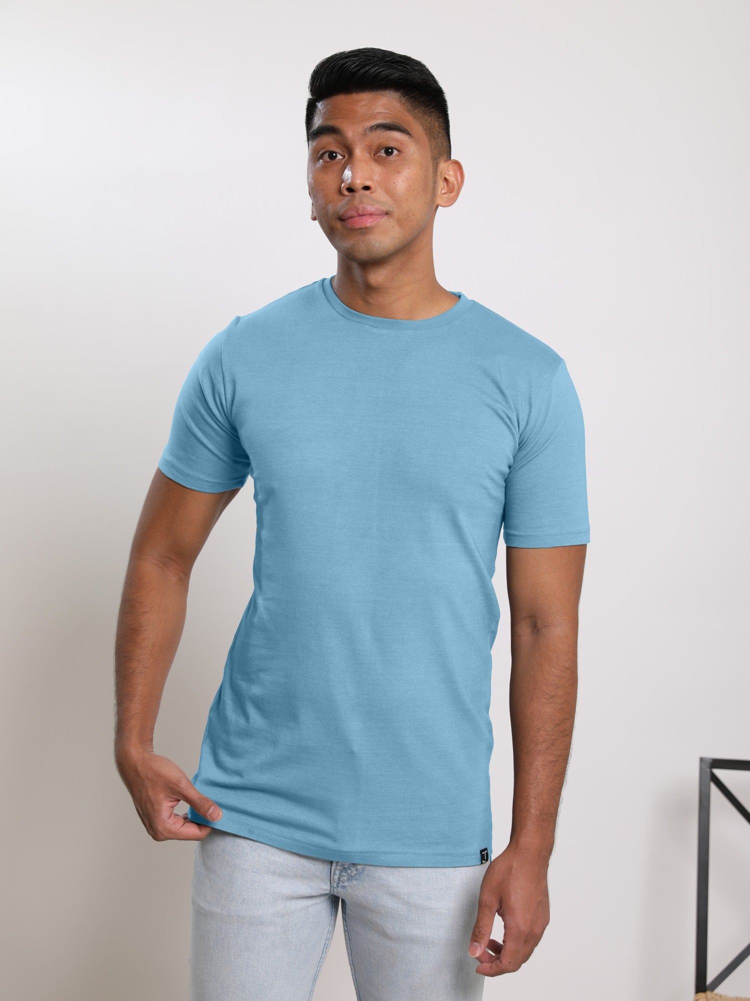 A studio shot of a tall slim guy wearing a medium tall slim pastel blue t-shirt.