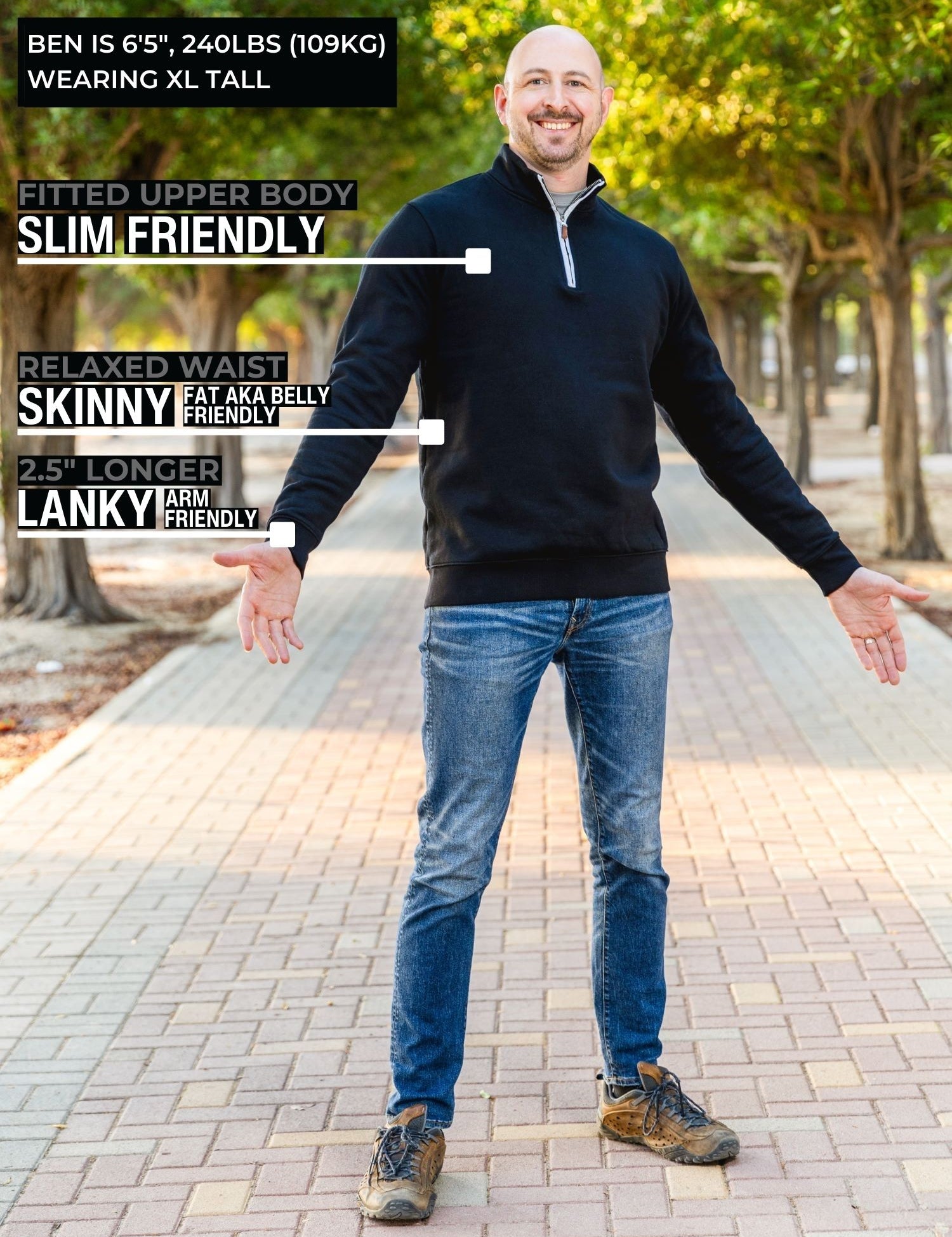 A head to toe shot of a tall slim guy in a park wearing an XL tall extra long black quarter zip sweatshirt.