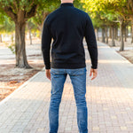 A shot from behind of a tall slim guy in a park wearing an XL tall extra long black quarter zip sweatshirt.