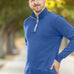 A tall and slim man standing on a path in  a park. The smiling model is wearing a cobalt quarter zip sweatshirt. The tall cobalt quarter zip sweatshirt features 2.5" longer sleeves, 100% organic french terry cotton, and is soft & comfy. It's  ideal for tall slim men 6'2"+.