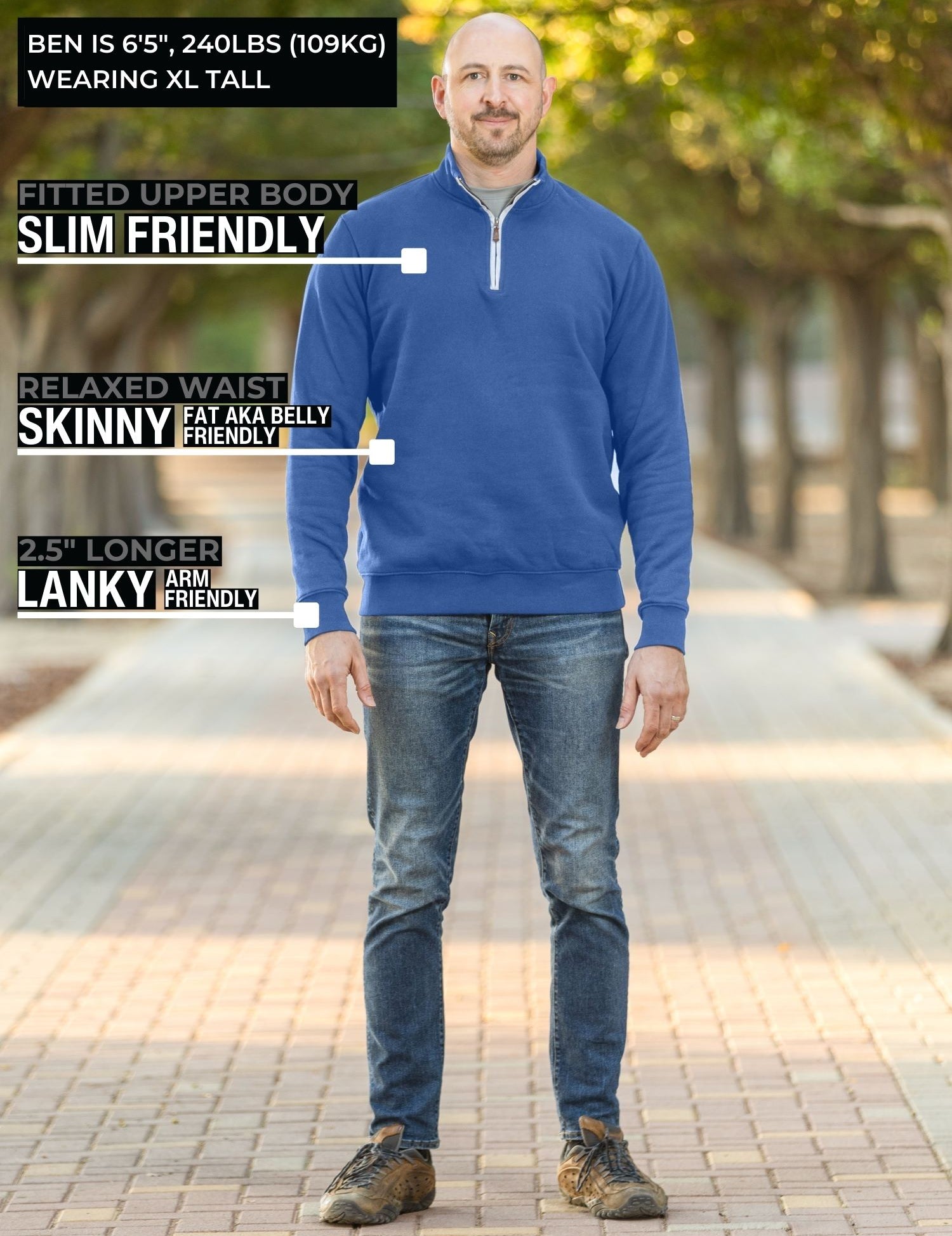 A head to toe shot of a tall slim guy in a park wearing an XL tall extra long cobalt quarter zip sweatshirt.