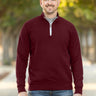 A tall and slim man standing on a path in  a park. The smiling model is wearing a maroon quarter zip sweatshirt. The tall maroon quarter zip sweatshirt features 2.5" longer sleeves, 100% organic french terry cotton, and is soft & comfy. It's  ideal for tall slim men 6'2"+.