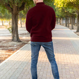 A shot from behind of a tall slim guy in a park wearing an XL tall extra long maroon quarter zip sweatshirt.