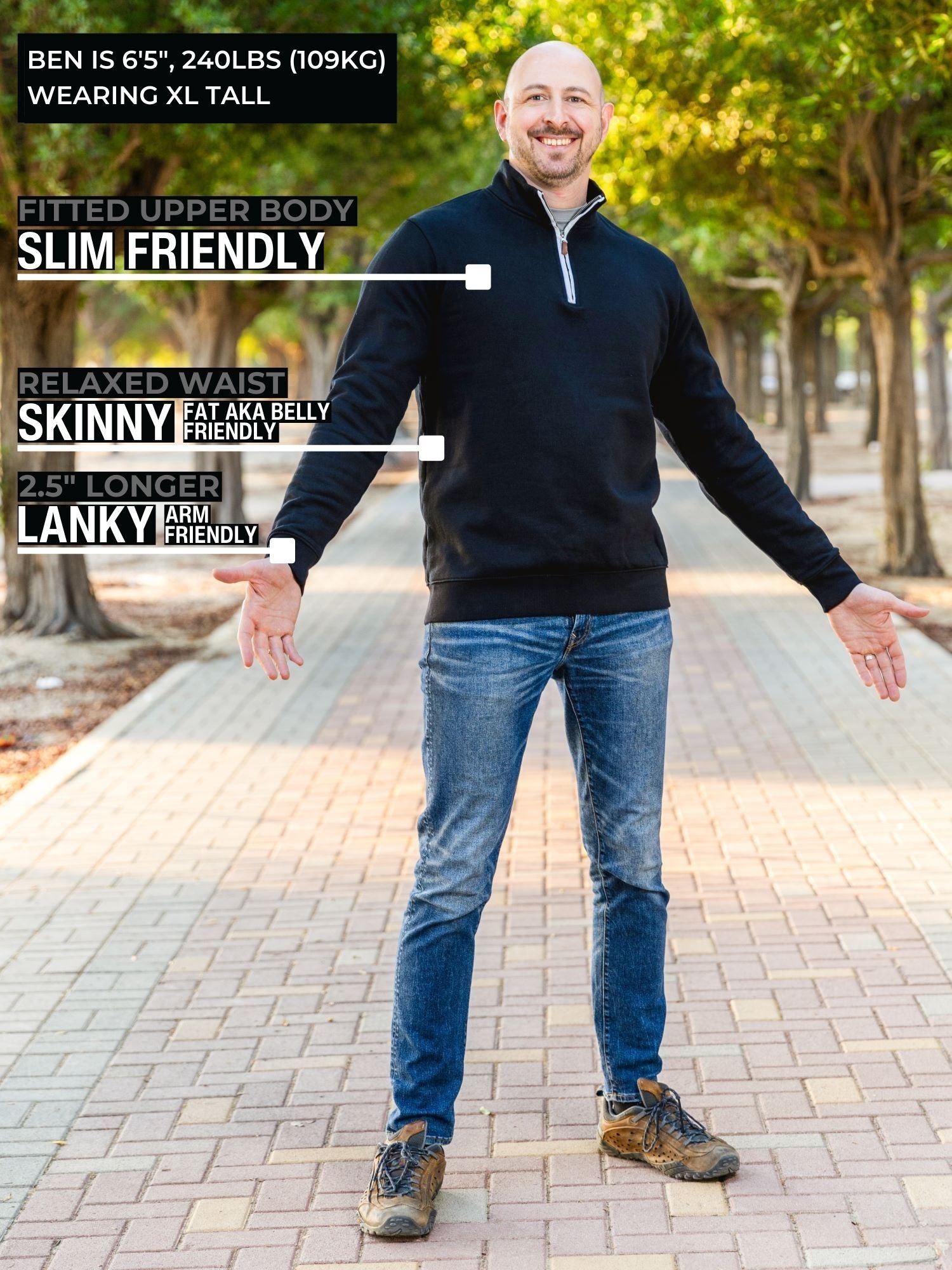 A head to toe shot of a tall slim guy in a park wearing an XL tall extra long black quarter zip sweatshirt.