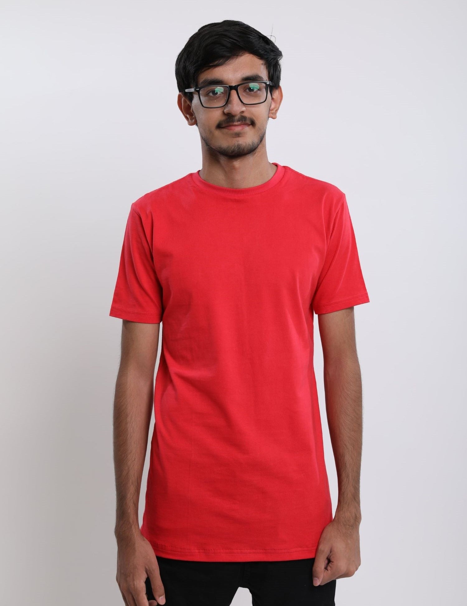 A tall and skinny man in the studio standing in front of a light background. The model is wearing an extra long slim red t-shirt. The red t-shirt features a 3" longer body, 100% organic cotton, and is soft & preshrunk. The red t-shirt is ideal for tall slim men 6'2"+.