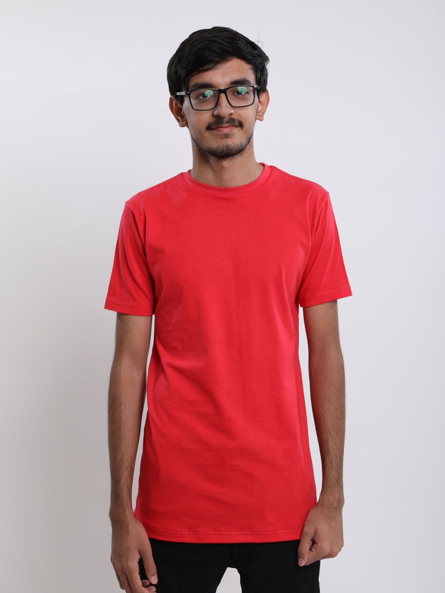 A tall and skinny man in the studio standing in front of a light background. The model is wearing an extra long slim red t-shirt. The red t-shirt features a 3" longer body, 100% organic cotton, and is soft & preshrunk. The red t-shirt is ideal for tall slim men 6'2"+.