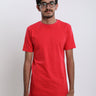 A tall and skinny man in the studio standing in front of a light background. The model is wearing an extra long slim red t-shirt. The red t-shirt features a 3" longer body, 100% organic cotton, and is soft & preshrunk. The red t-shirt is ideal for tall slim men 6'2"+.