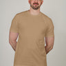 A tall and slim man in the studio standing in front of a light background. The model is wearing an extra long slim tan t-shirt in a size XL. The tan t-shirt features a 3" longer body, 100% organic cotton, and is soft & preshrunk. The tan t-shirt is ideal for tall slim men 6'2"+.