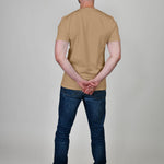 A shot from behind of a tall and slim guy in the studio and wearing a tan XL tall slim t-shirt.