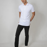 A head to toe shot of a tall slim guy in a studio and wearing a white M tall polo shirt.