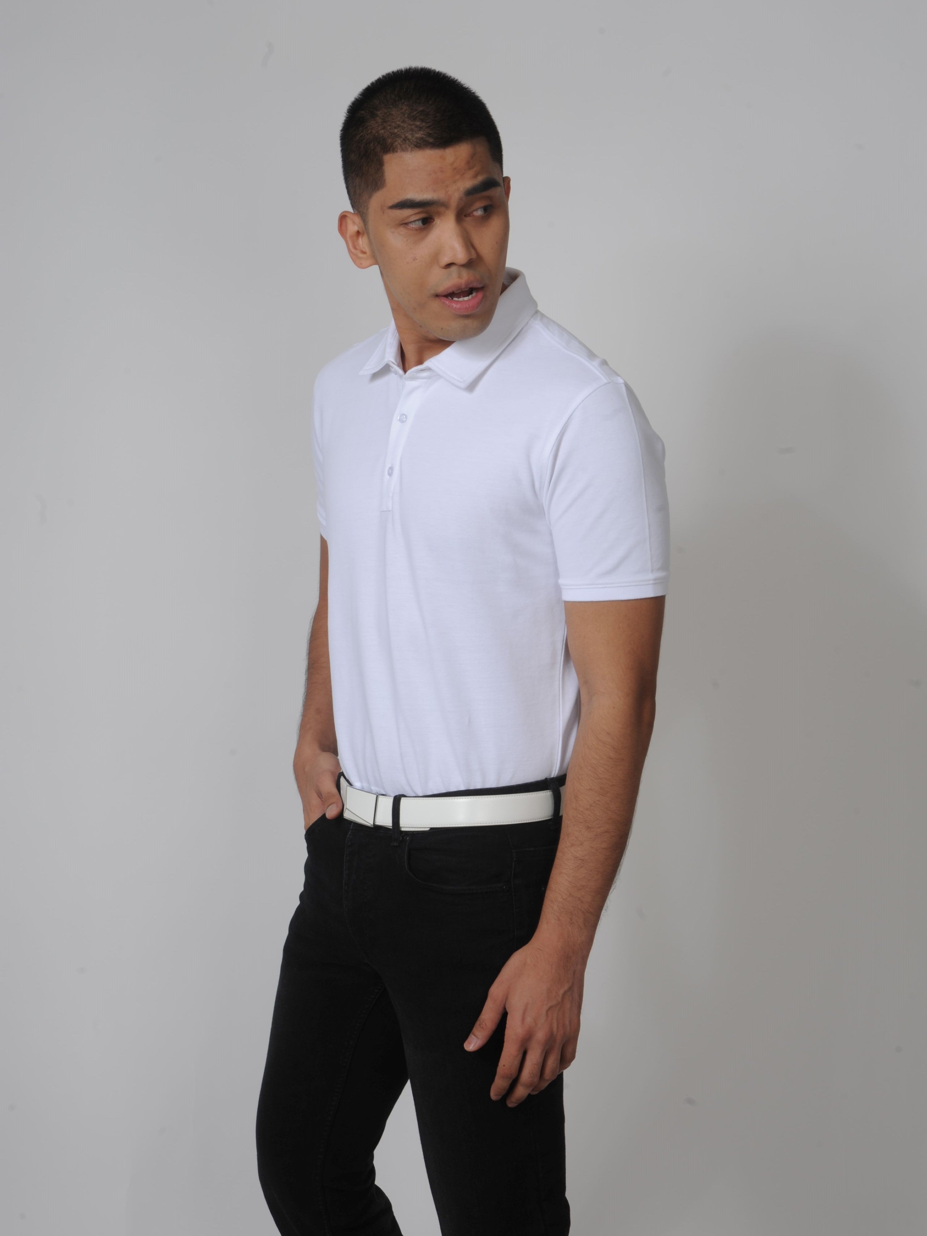 A tall slim guy in a studio and wearing a white M tall polo shirt.