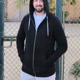 A tall slim guy wearing an XL tall black hoodie with hands in pockets and hood on, standing in a tennis court.