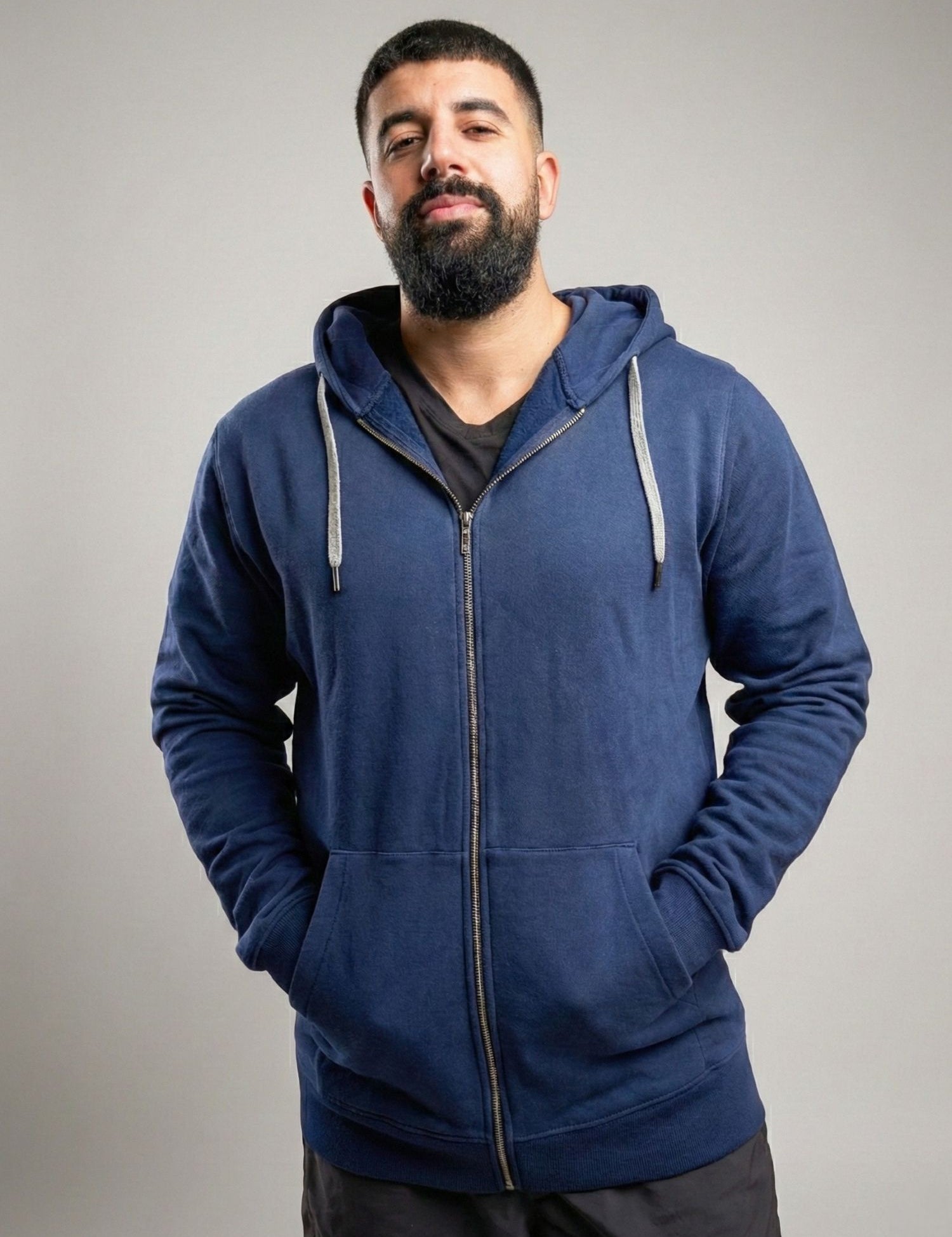 A tall and broad guy standing in a studio and wearing a 2XL Tall dark navy zip-up hoodie.