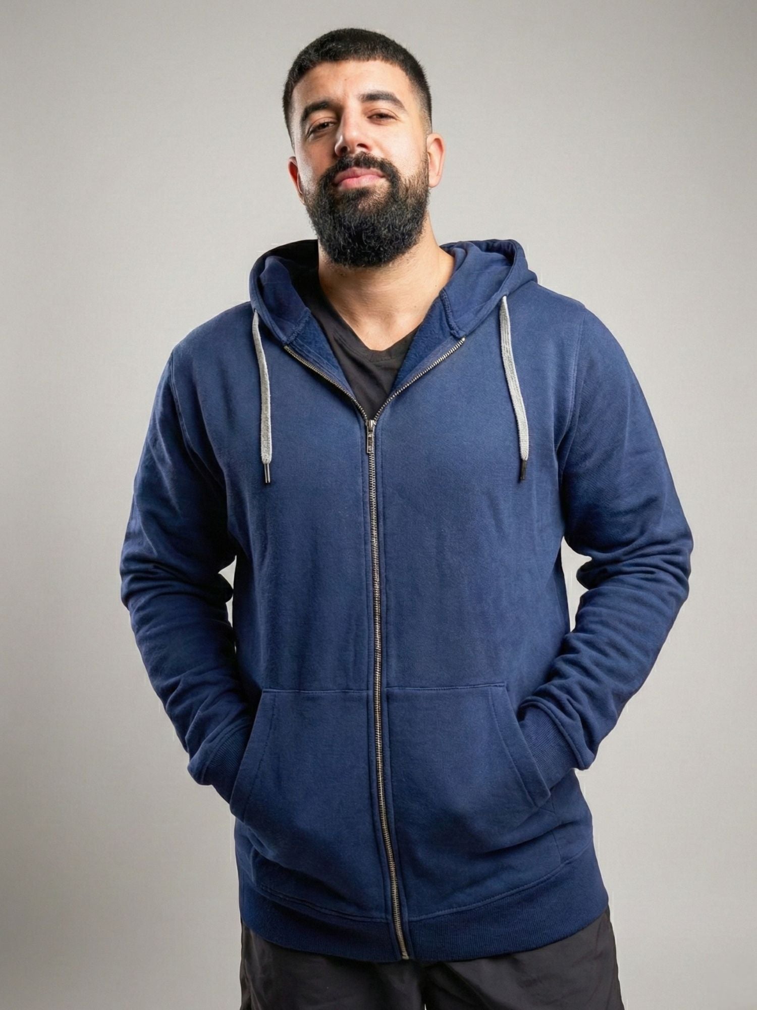 A tall and broad guy standing in a studio and wearing a 2XL Tall dark navy zip-up hoodie.