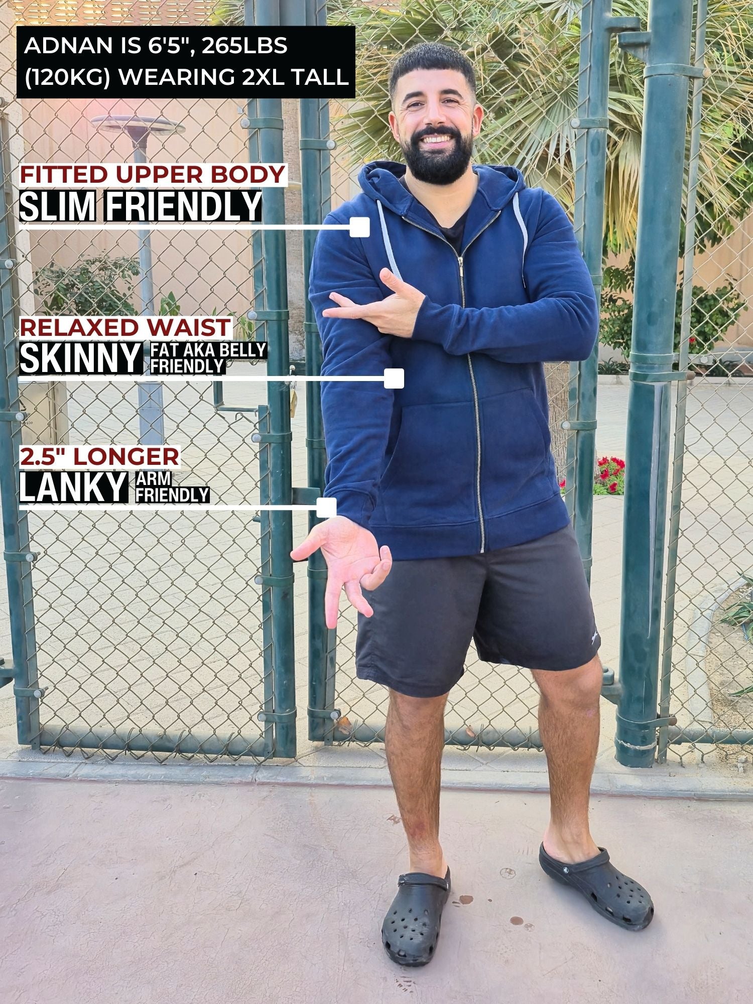 A head to toe shot of a tall and broad guy standing in a tennis court and wearing a 2XL Tall dark navy zip-up hoodie.