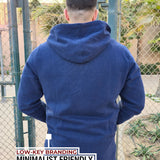 A shot from behind of a tall and broad guy standing in a tennis court and wearing a 2XL Tall dark navy zip-up hoodie.
