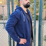 A side on shot of a tall and muscular guy standing in a tennis court and wearing an XL tall slim dark navy hoodie.