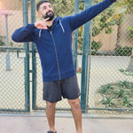 A tall and muscular guy standing in a tennis court and wearing an XL tall dark navy hoodie.