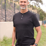 A tall skinny guy wearing a tall black henley shirt and smiling.