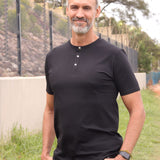 A tall skinny guy wearing a tall black henley shirt and smiling.