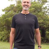 A tall skinny guy wearing a tall black henley shirt and laughing.