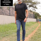 A head to toe shot of a tall skinny guy wearing a tall black henley shirt.