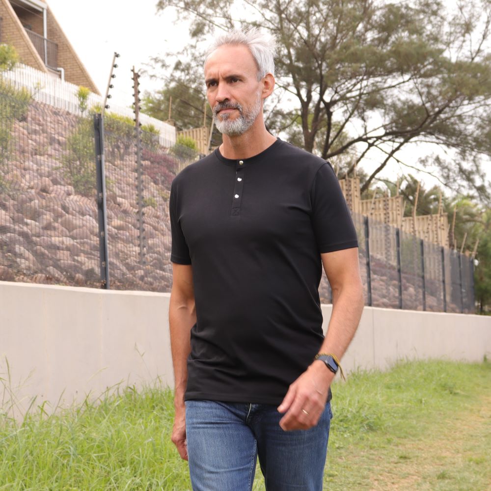 A tall slim guy wearing a black tall henley shirt.