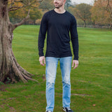 A head to toe shot of a tall athletic guy in a park wearing a black long sleeve tall t-shirt, looking to the right