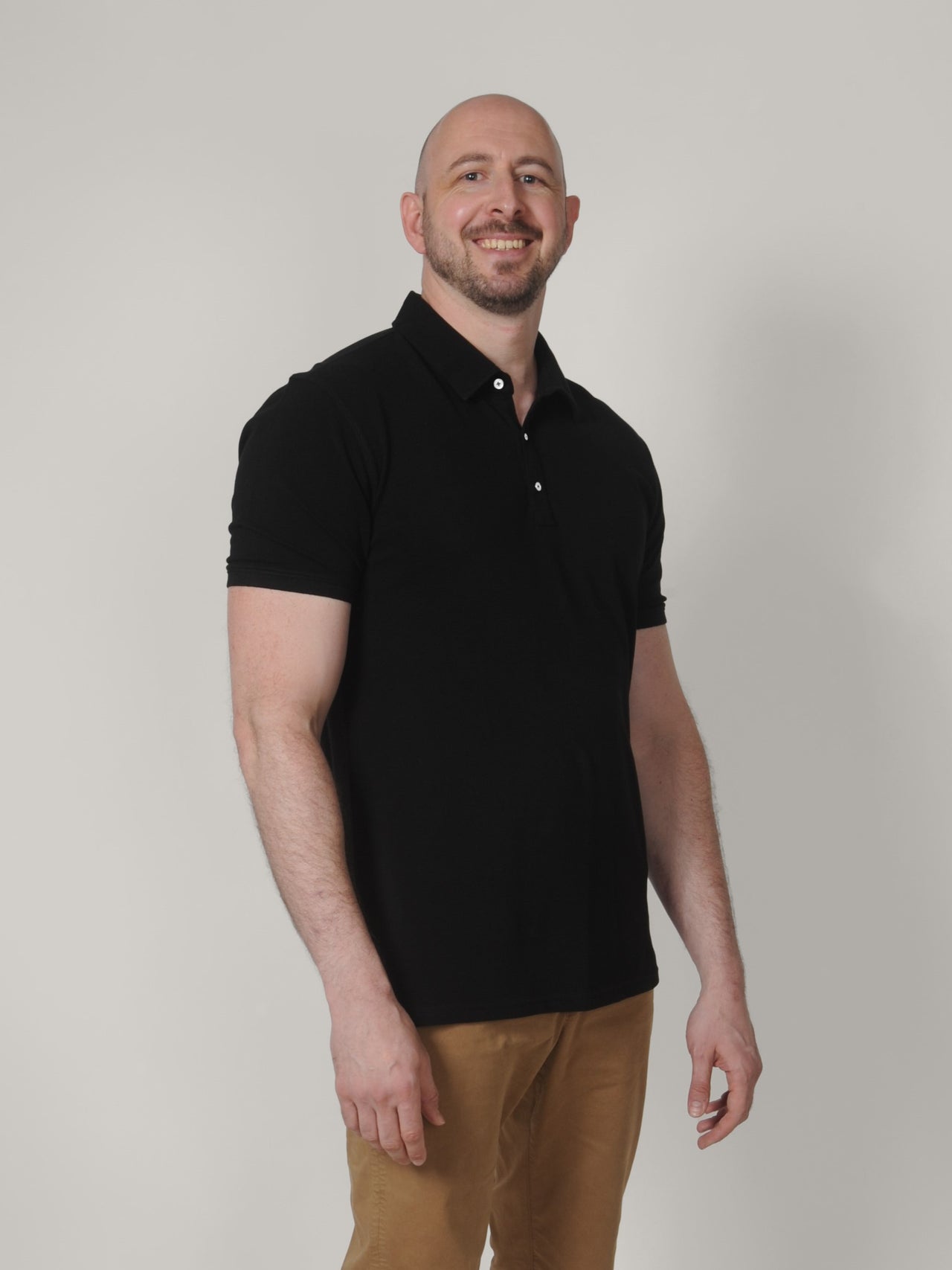 A tall skinny guy wearing a black XL tall polo shirt.