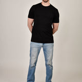A head to toe shot of a tall and slim guy in the studio wearing a black XL tall slim t-shirt.