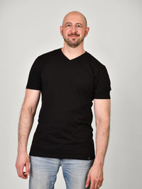 Thumbnail for A tall and slim guy smiling in the studio and wearing a black XL tall slim v-neck t-shirt.