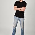 A head to toe shot of a tall and slim guy in the studio wearing a black XL tall slim v-neck t-shirt.