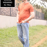 A head to toe shot of a tall skinny guy wearing a tall brown henley shirt.