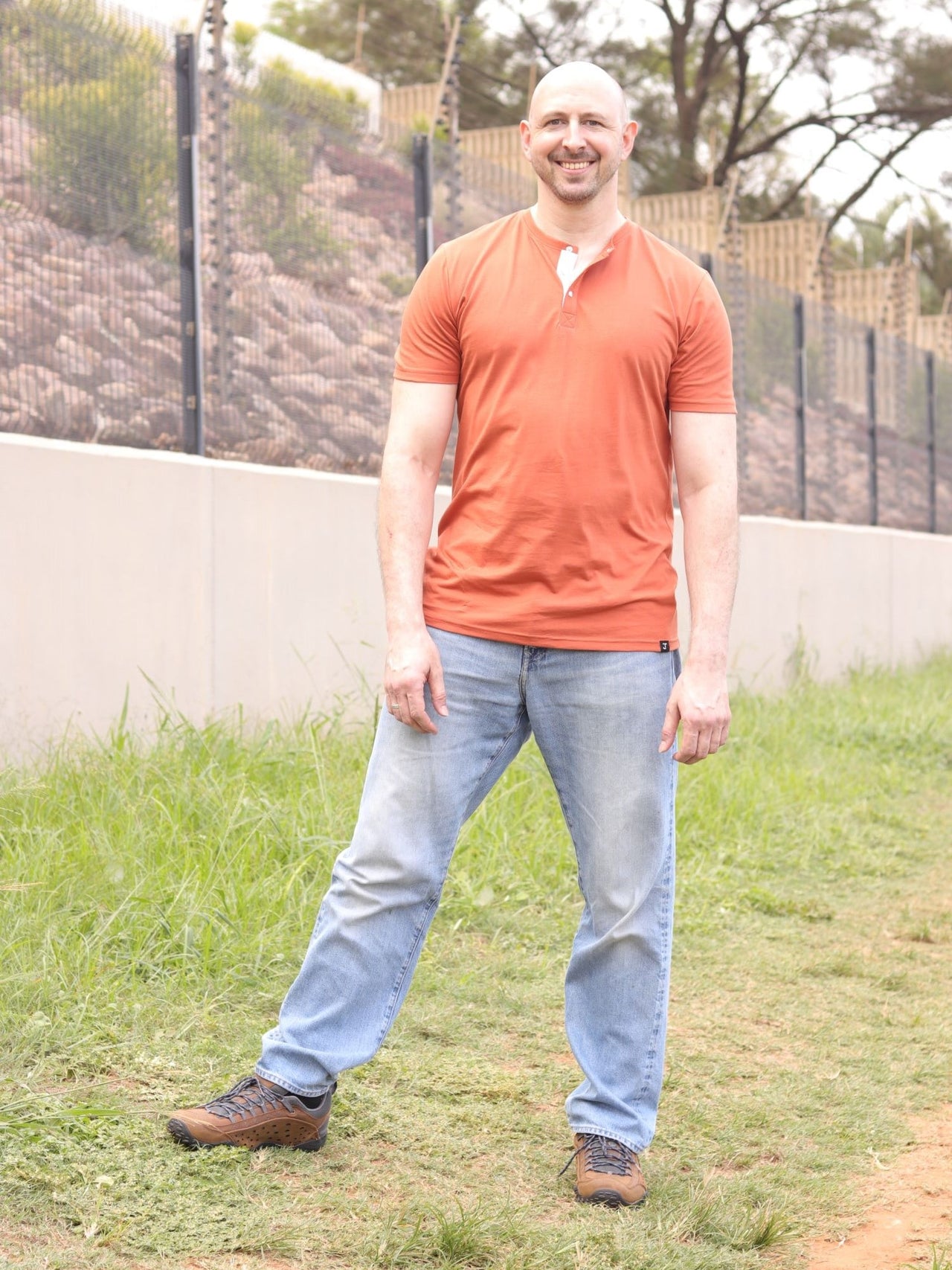 A tall skinny guy wearing a tall brown henley shirt and smiling.
