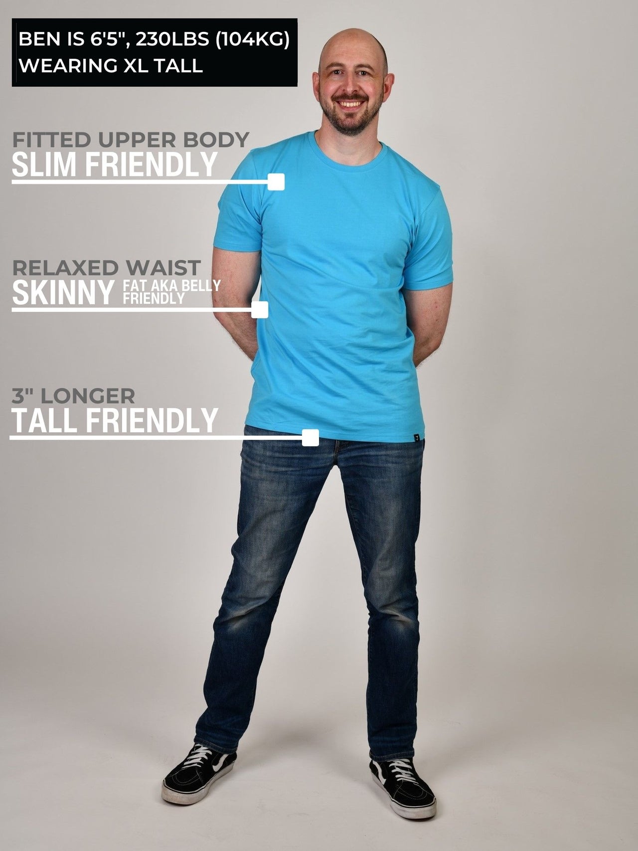 A head to toe shot of a tall athletic guy wearing a cyan XL tall t-shirt and smiling.