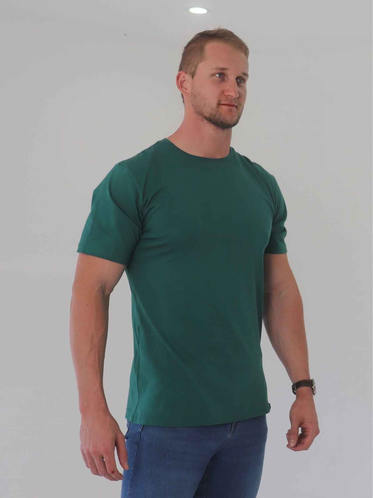 A tall and broad guy in the studio and wearing a dark green 2XL tall slim t-shirt.